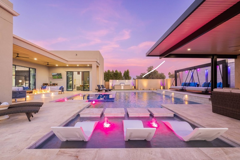 Luxurious Scottsdale vacation home with a modern pool, hot tub, outdoor seating, and scenic sunset sky.