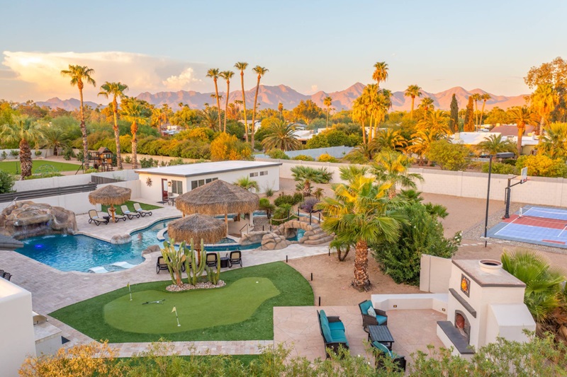 Scottsdale vacation home with a pool, hot tub, palm trees, a putting green, and mountain views in the background.