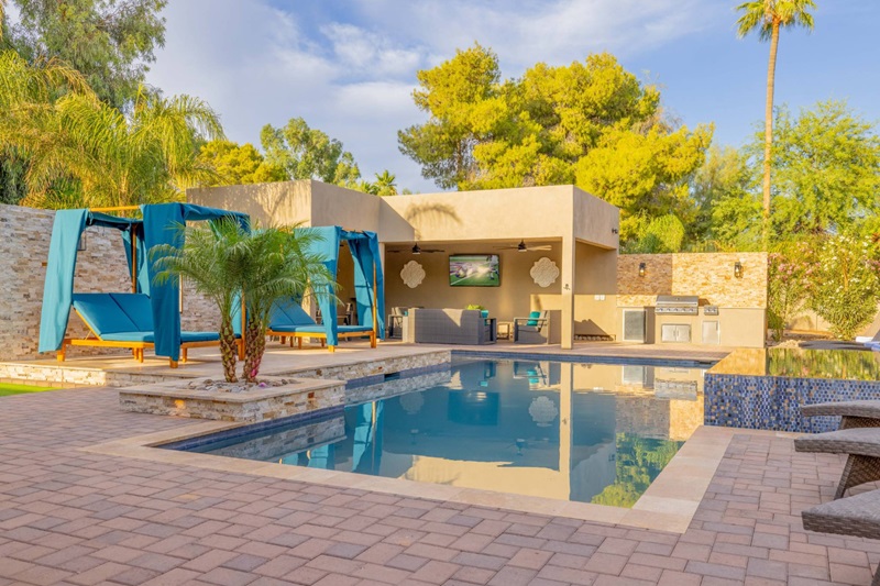 Luxury Scottsdale vacation home with a pool, outdoor lounge, and lush greenery, perfect for an elite golf getaway.