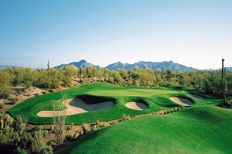 Scenic view of Legend Trail Golf Club in Scottsdale, Arizona, with lush green fairways, sand bunkers, desert landscape, and mountains in the background.