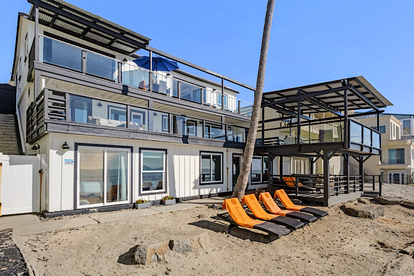 Beachfront luxury 10-bedroom home in San Diego with multiple decks, outdoor lounge chairs, and ocean views.
