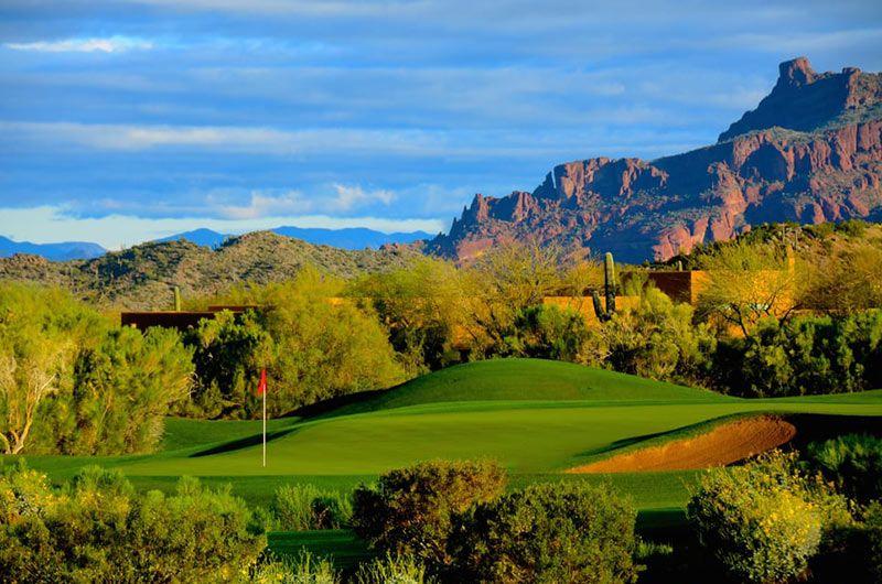 Scenic golf course in Arizona with lush green fairways, desert landscape, and rugged mountains in the background.