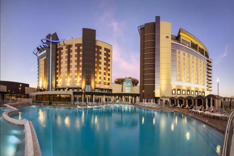 Luxury hotel buildings with a large outdoor pool, surrounded by lounge chairs, at Gila River Resorts & Casinos - Wild Horse Pass.