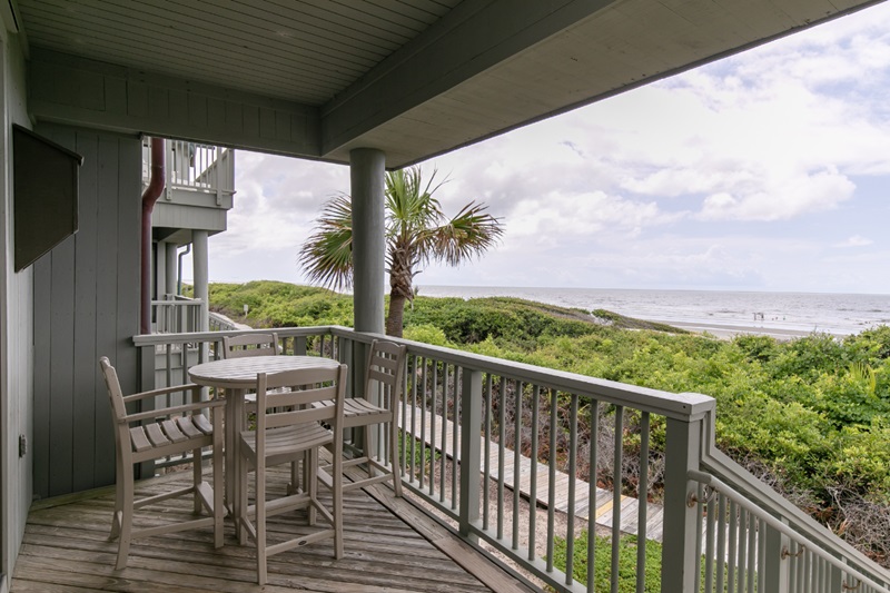 Resort Villas - Kiawah Island Resort Balcony view of Kiawah Island Resort with outdoor furniture, lush greenery, and ocean in the background.