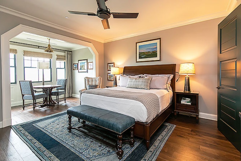 The Cottages at The Ocean Course - Kiawah Island Resort Luxury bedroom at The Cottages of The Ocean Course, Kiawah Island Resort, featuring a large bed, nightstands, lamps, and a sitting area.