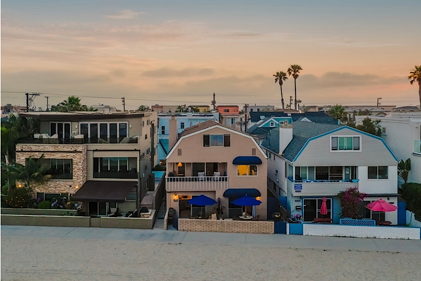 Colorful beachfront houses in San Diego, CA, with palm trees and a sunset sky, near golf clubs and local attractions.