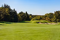 Scenic view of a golf course fairway with sand traps, lush green grass, and trees under a clear blue sky at TPC Osprey Valley.