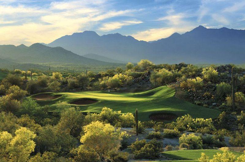 Scenic view of a golf course near the Golf Club of Estrella in Goodyear, Arizona, with mountains in the background and lush greenery.
