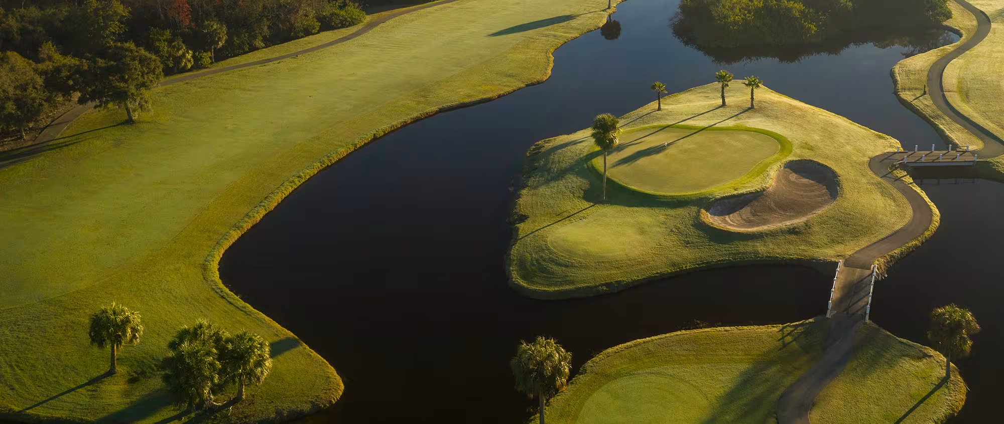 Aerial view of a scenic Florida golf course with water hazards, lush green fairways, and palm trees, perfect for golf vacations.