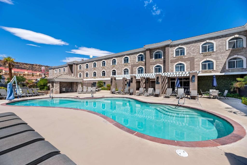 Outdoor swimming pool at Best Western Plus Abbey Inn in St. George, with lounge chairs, umbrellas, and a hotel building in the background.