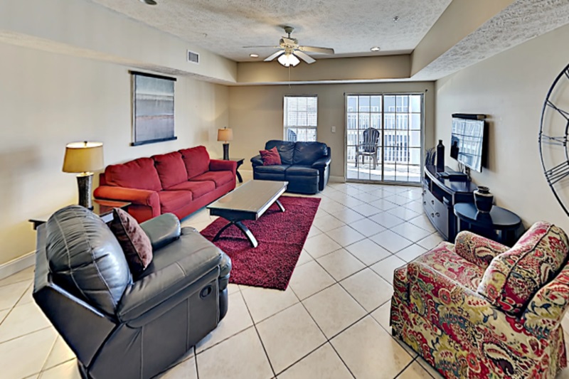 Myrtle Beach Villas - 201A Living room in Myrtle Beach Villas II condo with colorful sofas, a TV, and a balcony with ocean and golf course views.