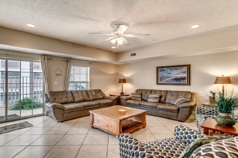 Myrtle Beach Villas - 205A Living room in Myrtle Beach Villas 205A, a luxury 4-bedroom condo with leather sofas, a coffee table, and a balcony view.