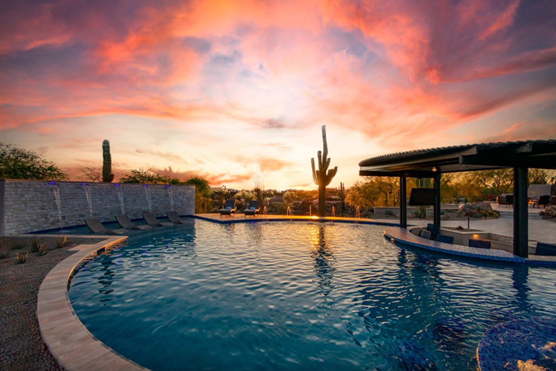 Luxury desert estate with a pool, cactus, and sunset sky, perfect for a golf getaway in Scottsdale's Lost Canyon.