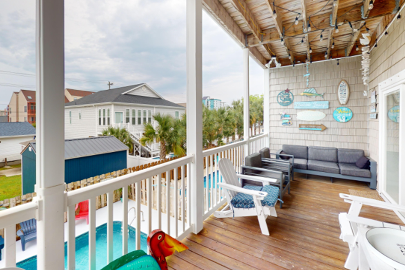 Bermuda Breeze - A A balcony with outdoor seating, ocean views, and beach-themed decorations, part of the Bermuda Breeze luxury villa.