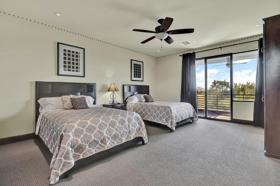 Spacious hotel room with two beds, a balcony view of trees, a ceiling fan, and modern decor at Quintero.