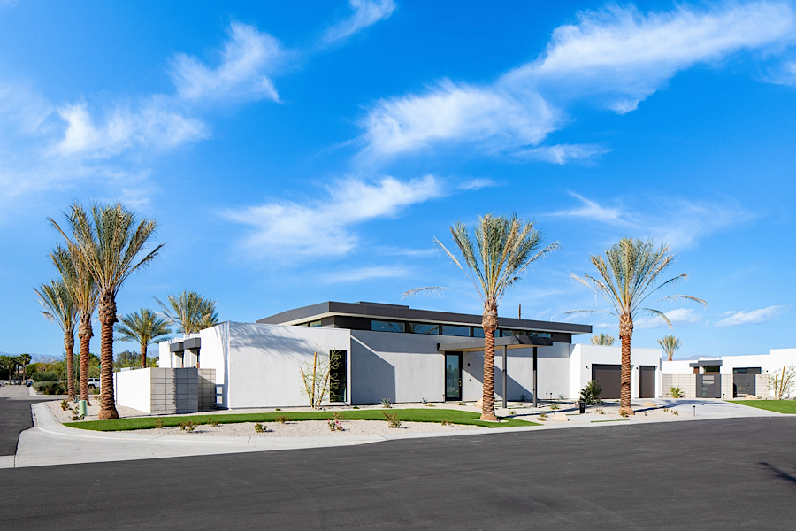 Modern luxury house with palm trees, a clear blue sky, and a clean driveway in Coachella Valley, California.