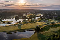Aerial view of Thistle Stewart/MacKay Scottish-links golf course in Myrtle Beach at sunset, featuring greens, water hazards, and trees.