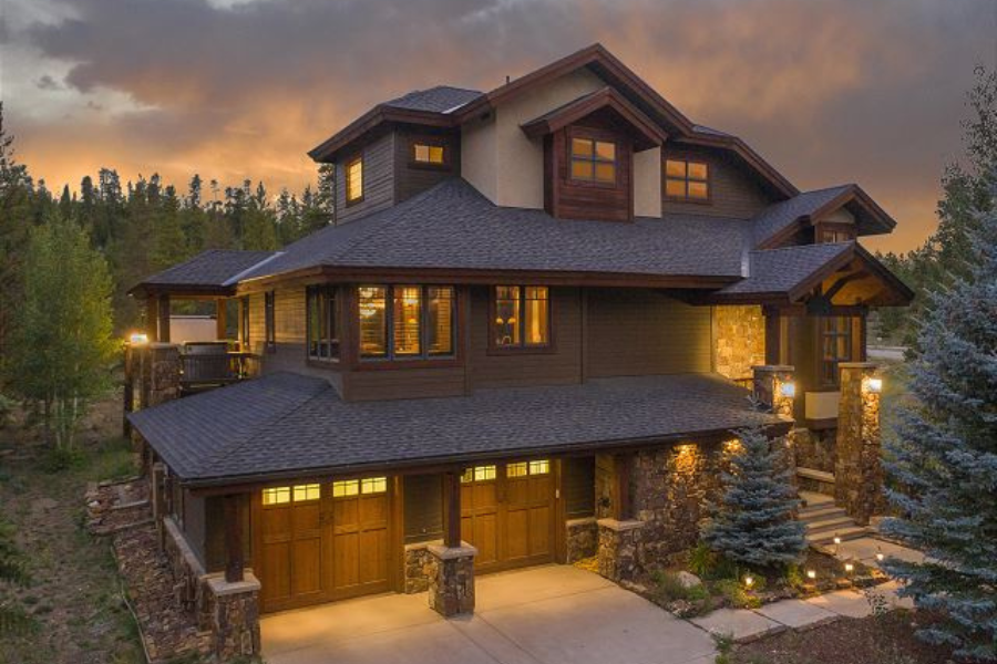 Luxurious mountain home in Keystone, Colorado, with multiple levels, large windows, stone accents, and warm exterior lighting.