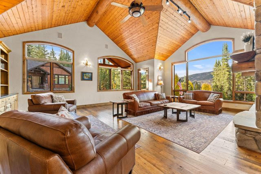Luxurious living room in a Colorado Rockies vacation home with large windows, wooden ceiling, and mountain views.