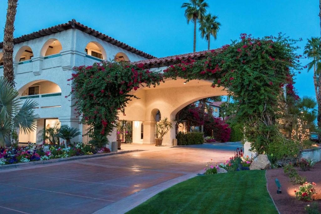Las Brisas Hotel Luxurious Las Brisas Hotel in Palm Springs with Mediterranean architecture, lush gardens, and vibrant flowering plants at dusk.