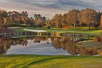 Scenic Orange Lake Golf Legends Course with lush greens, trees, water hazard, and a sand trap, designed by Arnold Palmer.
