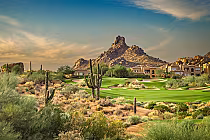 Scenic view of Troon North golf course with desert landscape, cacti, green fairways, and rocky mountain backdrop at sunset.