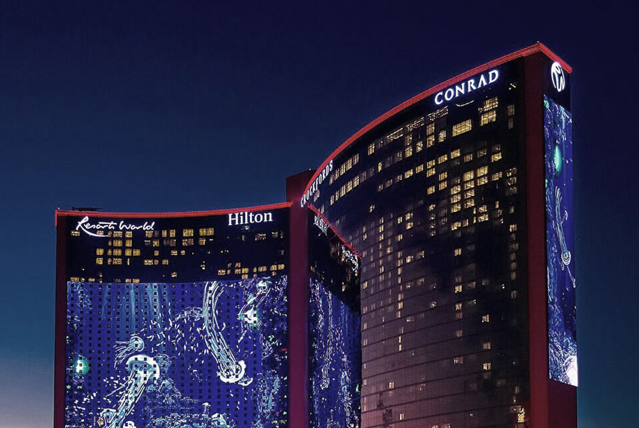 Conrad Las Vegas at Resorts World Night view of the Conrad Las Vegas at Resorts World, a modern high-rise hotel with illuminated signs and digital displays.
