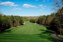 Scenic view of Bay of Quinte G&CC North Course with lush green fairway, surrounded by trees under a blue sky with scattered clouds.