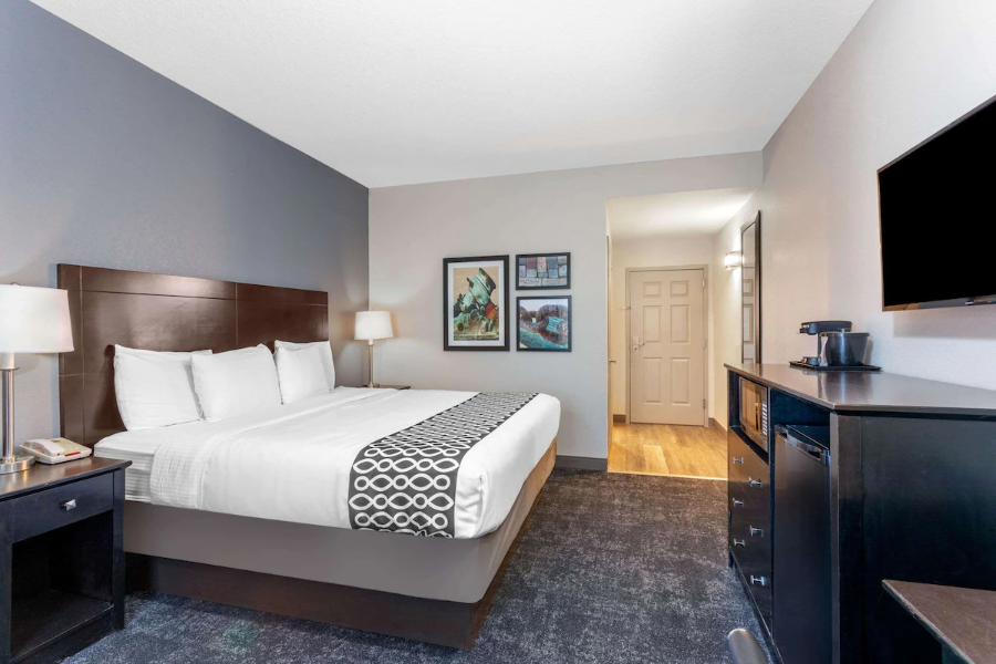 Modern hotel room with a king bed, stylish decor, TV, and coffee maker at La Quinta Inn, St. Augustine.