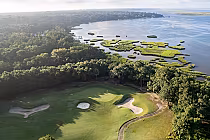 Aerial view of Amelia River Club golf course with lush green greens, sand bunkers, surrounded by trees and water bodies in North Florida.