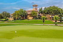 Golf course with a green, flags, trees, and a clubhouse in the background at Falcon's Fire Golf Club, Orlando.