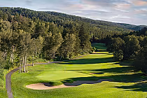 Scenic view of EagleVail Golf Club with lush green fairways, sand bunkers, surrounded by dense trees and mountain backdrop.