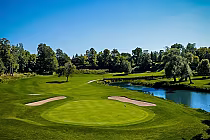 Scenic golf course with lush green fairways, sand bunkers, a water hazard, and trees under a clear blue sky at Nottawasaga Golf Course.