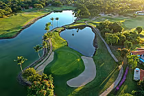 Aerial view of Casa De Campo golf course with lush green fairways, water hazards, palm trees, and scenic landscaping.