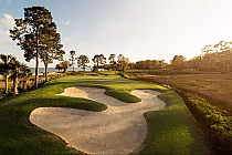 A scenic golf course on Daufuskie Island with coastal views, featuring sand bunkers, lush green fairways, and tall trees.