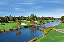 Scenic view of the George Fazio Course at Palmetto Dunes with lush green fairways, water hazards, and a wooden bridge over a river.