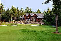 Lush golf course with sand traps leads to a rustic lodge surrounded by tall pine trees at Rocky Crest Golf Resort.