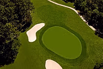 Aerial view of a lush green golf course with sand bunkers and trees at Julington Creek Golf Club under a clear sky.