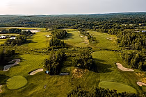 Aerial view of Timberwolf Golf Club featuring lush green fairways, sand bunkers, and surrounding dense forest landscape.