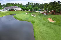 Aerial view of a lush golf course at TPC Myrtle Beach with well-maintained greens, sand traps, and a tranquil pond.