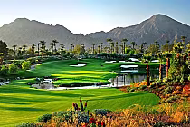 Lush golf course with vibrant greens, water features, and palm trees, set against a backdrop of mountains under a clear sky.