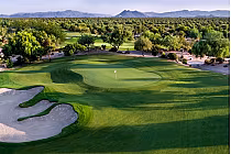 Lush green golf course with sand bunkers, surrounded by desert vegetation and distant mountains at JW Marriott Phoenix.