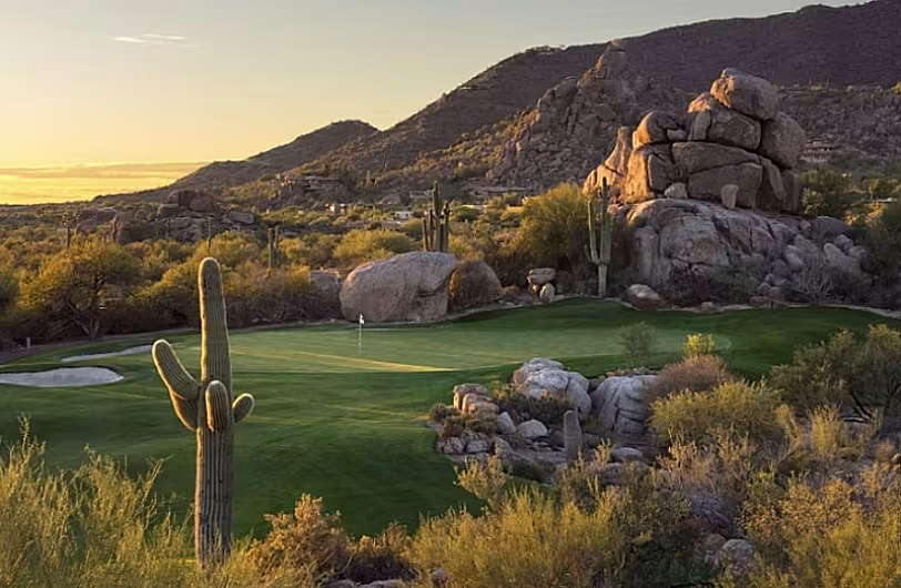 Scenic desert golf course in Scottsdale, AZ, surrounded by cacti and rocky hills at sunset, highlighting natural beauty.