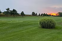 Sunset view over lush green Widder Station Golf Course with tees and distant trees in Lambton Shores, Ontario.
