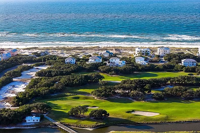 Aerial view of Kiva Dunes golf course, sandy beach, and blue ocean, with residential homes in Gulf Shores, Alabama.