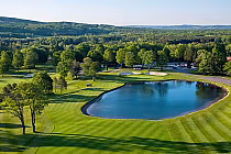 Aerial view of The Heather Course at The Highlands, Harbor Springs, featuring a lush green fairway and a serene pond.