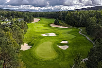 Scenic view of The Highlands golf course in Harbor Springs, MI, featuring lush green fairways and sand bunkers under cloudy skies.
