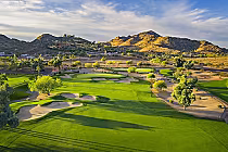 Scenic view of Lookout Mountain Golf Club with lush green fairways, sand bunkers, and desert mountains in the background.