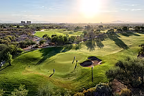 Sunny golf course with green fairways, sand bunker, and distant mountains at Whirlwind’s Devil’s Claw, Arizona.