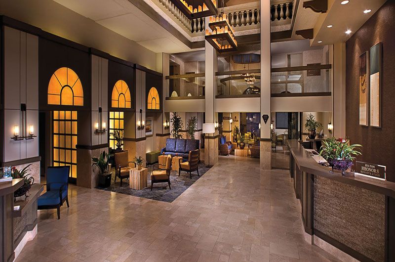 Elegant hotel lobby with warm lighting, modern decor, comfortable seating, and a reception desk at Hilton Phoenix Tapatio Cliffs Resort.